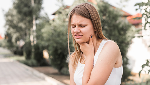 A girl outside who is having difficulty swallowing.