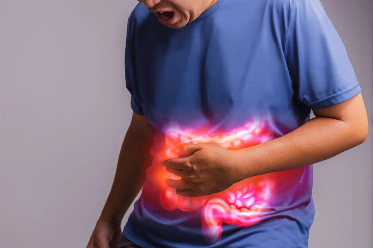 Crohns Disease Man with a pained expression clutching his abdomen with a superimposed image of glowing intestines indicating discomfort or pain.